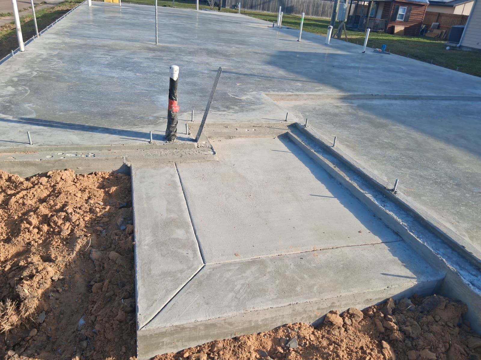 Completed concrete slab with formed edges and plumbing penetrations