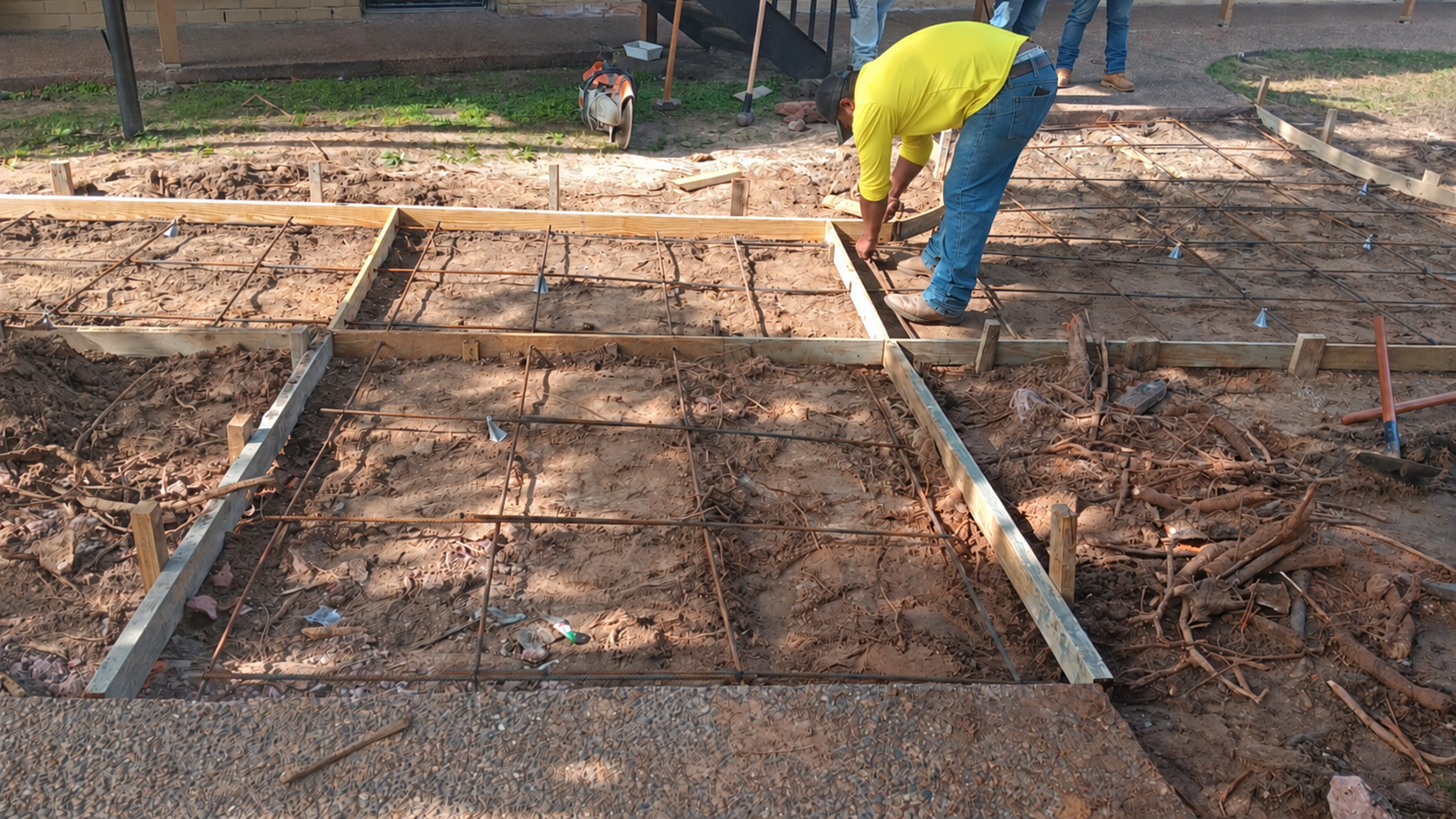 Worker preparing concrete formwork beside steel reinforcement