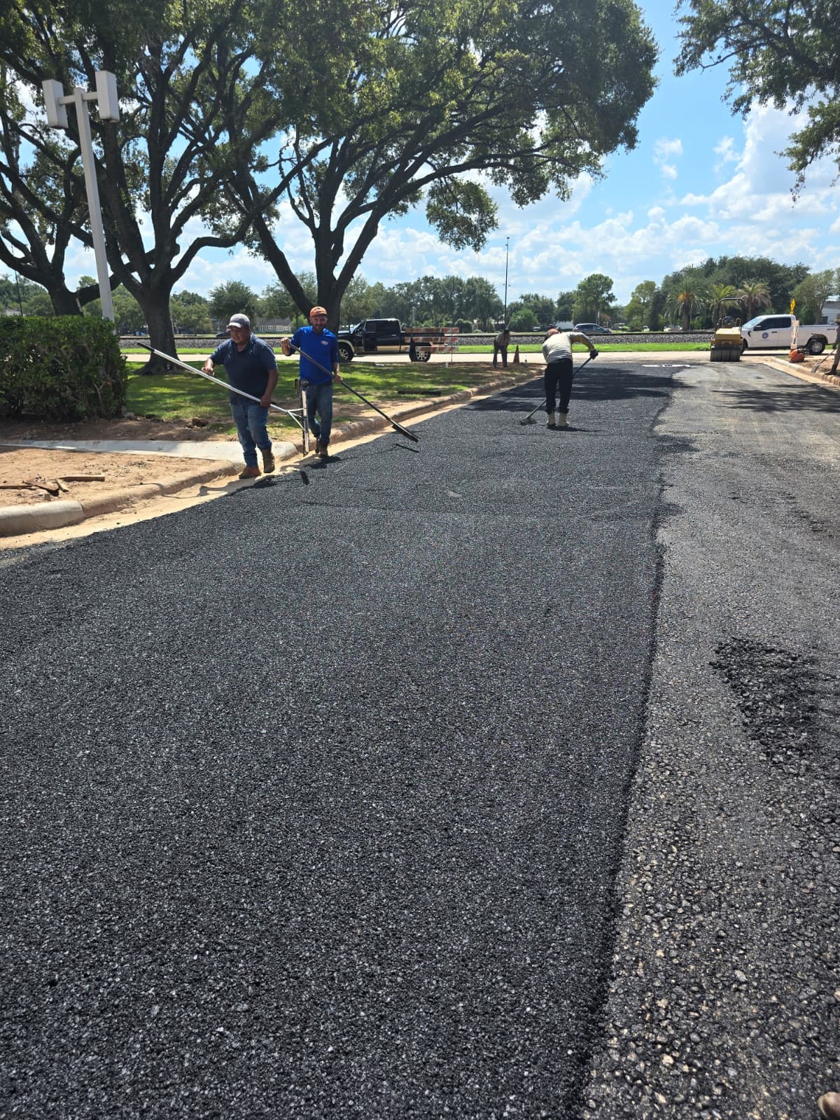 Crew finishing fresh asphalt pavement